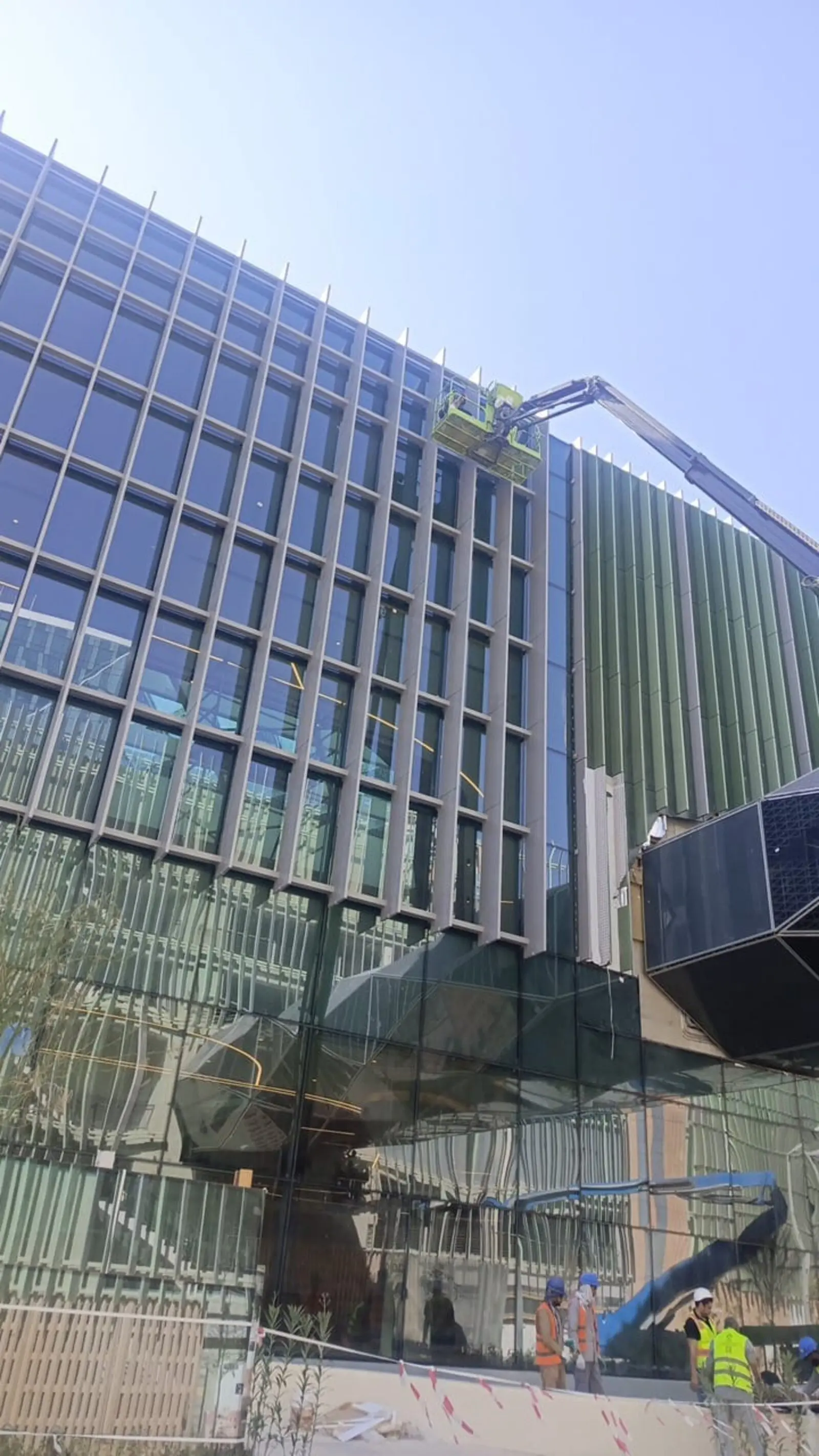 فريق شركة تنظيف واجهات بالرياض ينظف واجهة زجاجية وكلادينج أخضر لمبنى حديث بحي العارض باستخدام رافعة - حلول وتميز