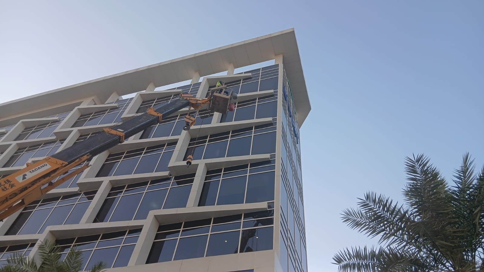 رافعة تابعة لشركة تنظيف واجهات مدارس وفنادق بالرياض تنظف واجهة زجاجية لفندق حديث - حلول وتميز