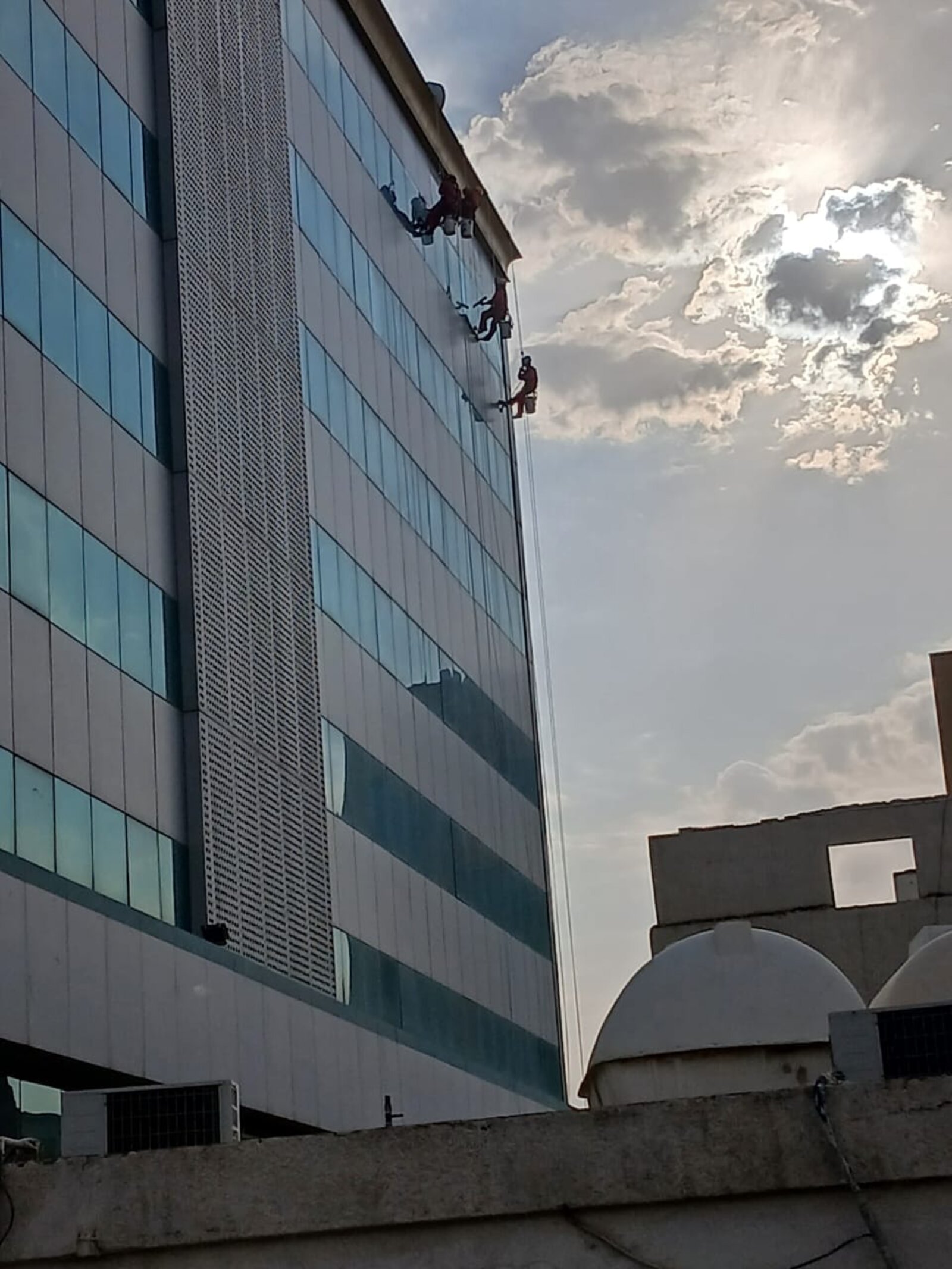 فريق شركة تنظيف واجهات زجاجية بالرياض ينظف واجهة برج زجاجي مرتفع بتقنية الحبال - حلول وتميز