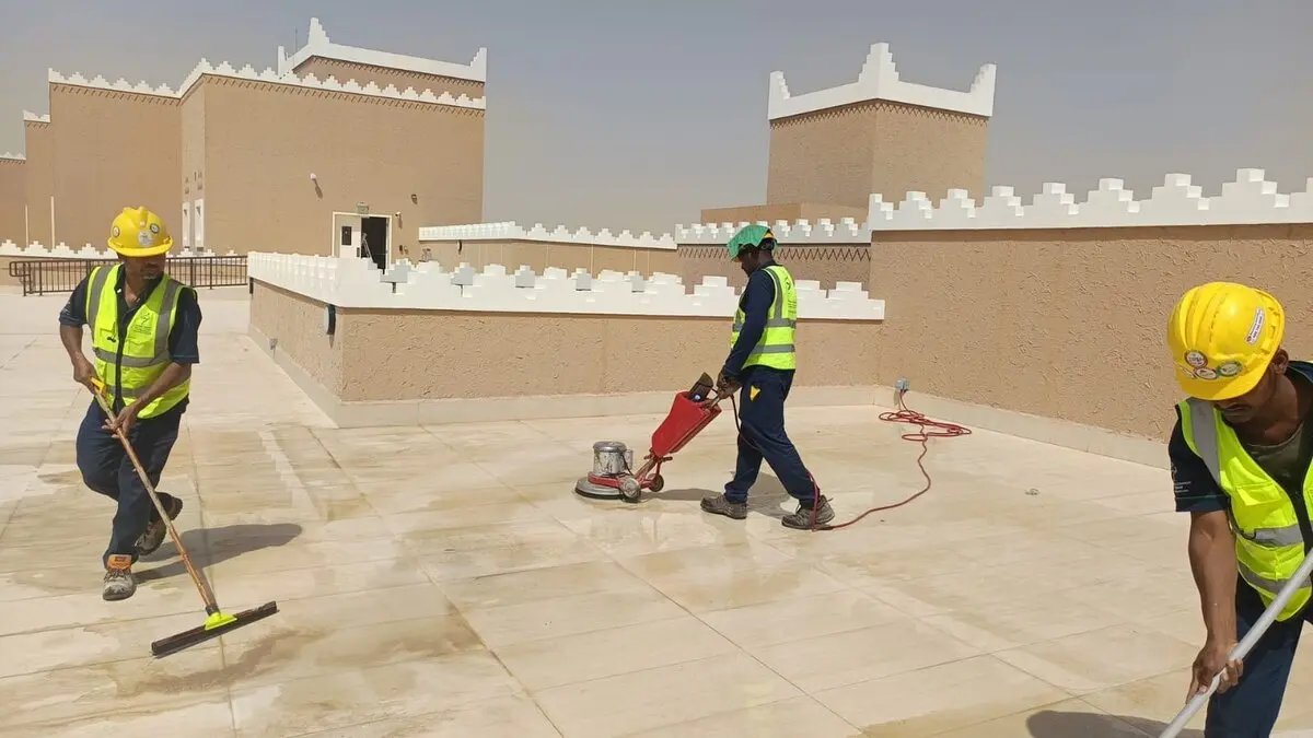 فريق من عمال شركة تنظيف منازل وفلل بالرياض يجلون أرضية سطح منزل بطراز نجدي بعد الترميم