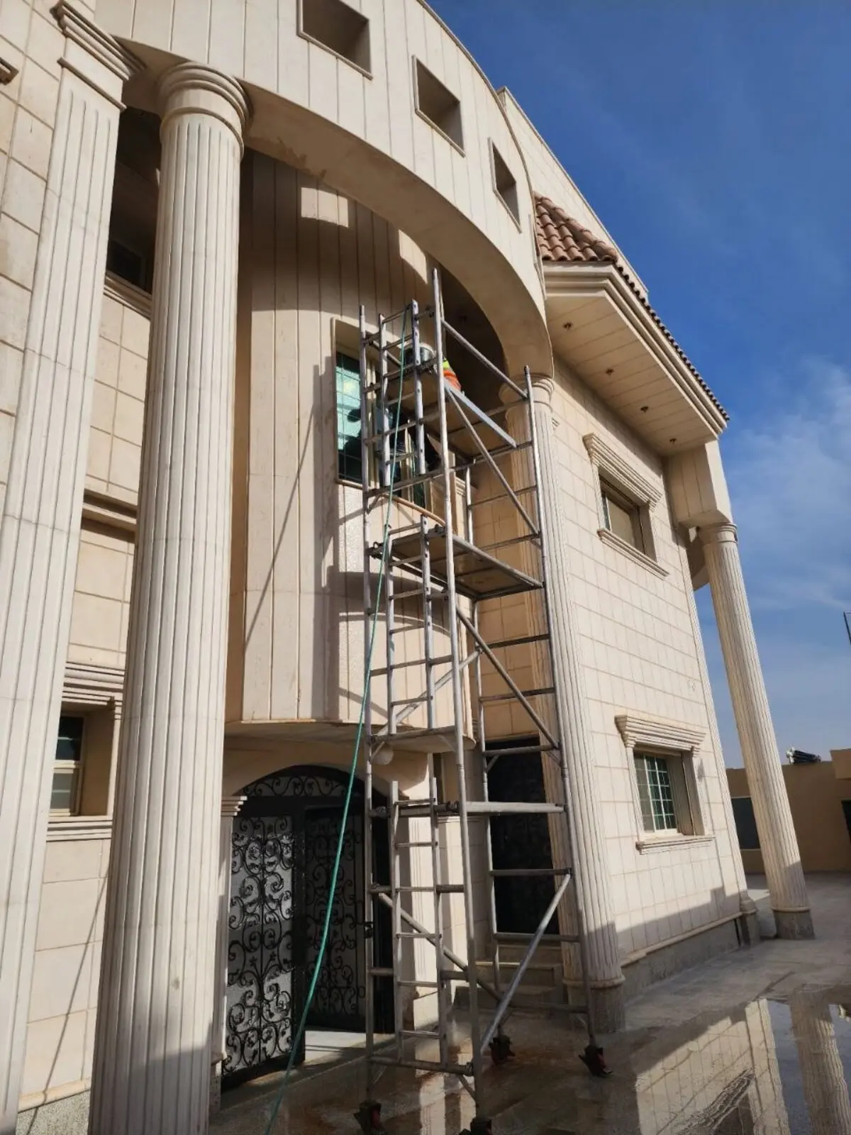 فريق شركة تنظيف بيوت وفلل بالرياض ينظف واجهة فيلا حجرية باستخدام برج سقالة وجهاز ضغط المياه العالي